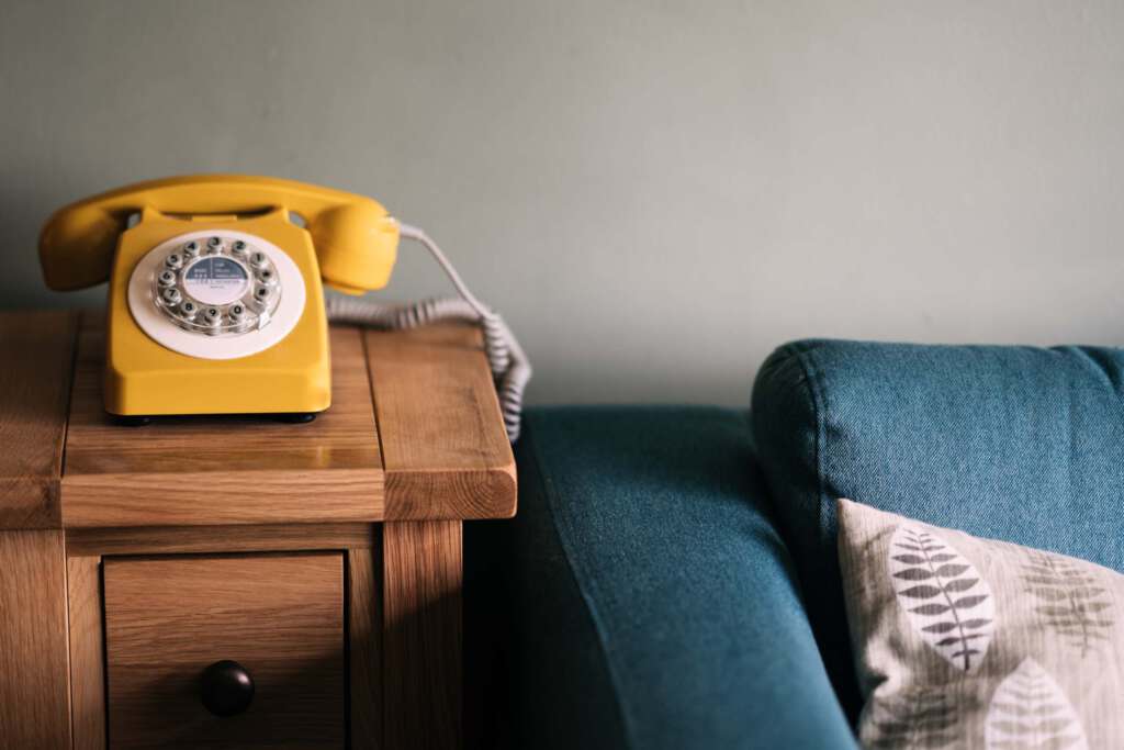 Gelbes Telefon auf einem Holztisch neben einer Couch