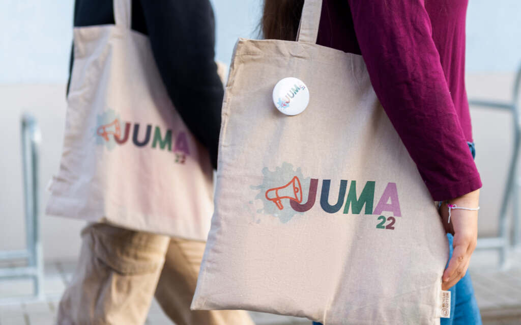 zwei Personen mit Stofftaschen, auf denen JUMA22 steht