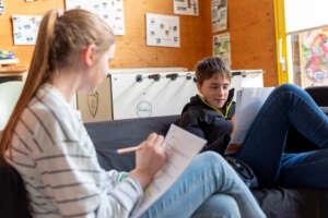 Zwei Personen sitzen auf einer Coach und arbeiten an Texten.