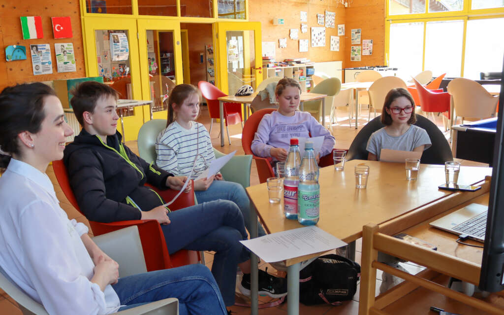 Fünf Personen sitzen am Tisch