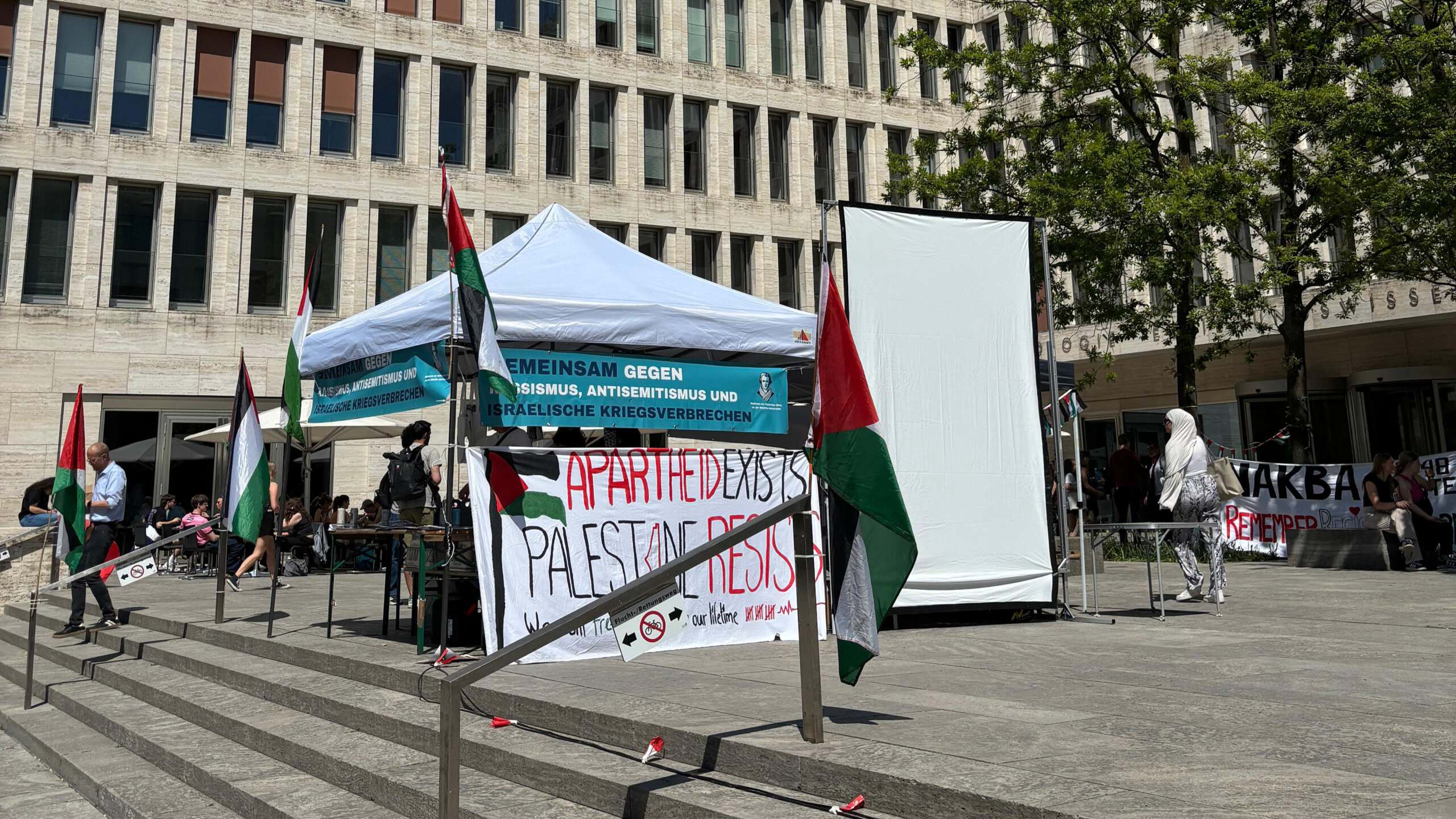 Zu sehen ist ein Stand und Banner mit der Aufschrift "Apartheid exists, Palestine resists."