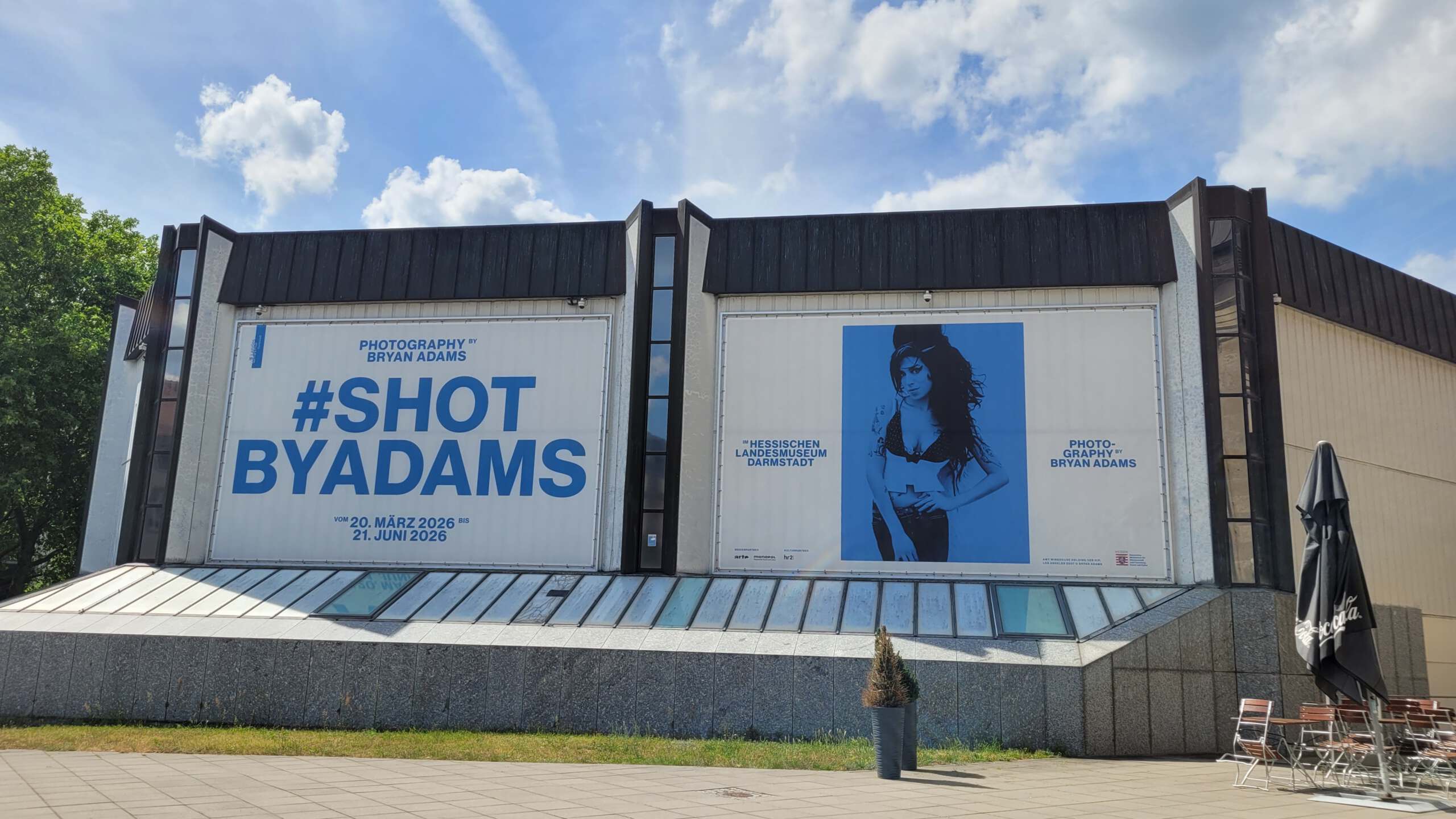 Plakat mit Amy Winehouse zur Ausstellung "Shot by Adams"